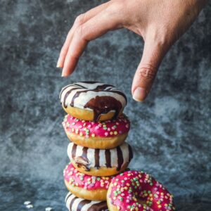 Delicious doughnuts in a stack, hand reaching from above taking one off the top